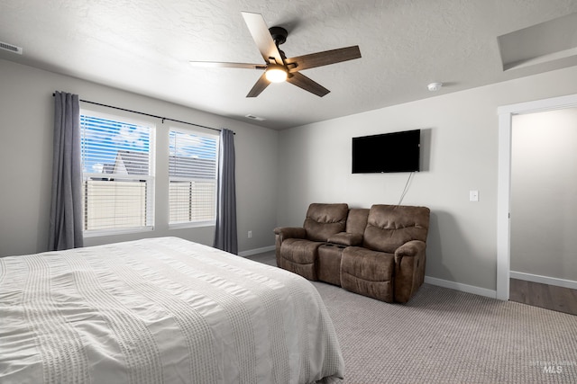 carpeted bedroom featuring visible vents, baseboards, a textured ceiling, and ceiling fan