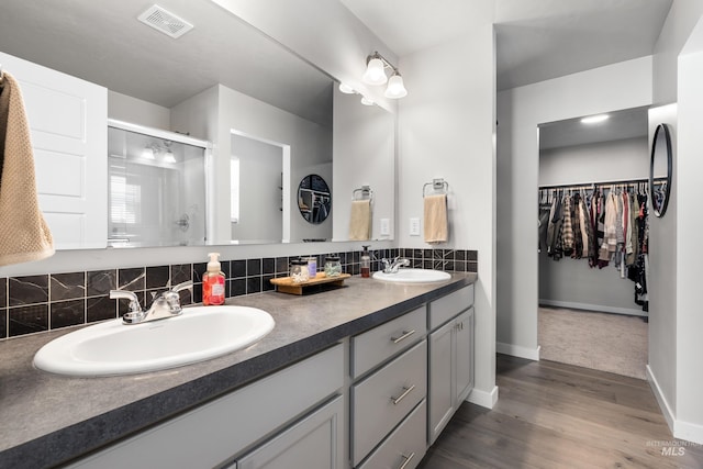 bathroom with a shower stall, baseboards, a sink, and double vanity