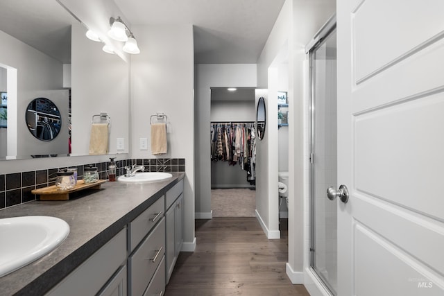 full bathroom with a sink, a stall shower, baseboards, wood finished floors, and a walk in closet