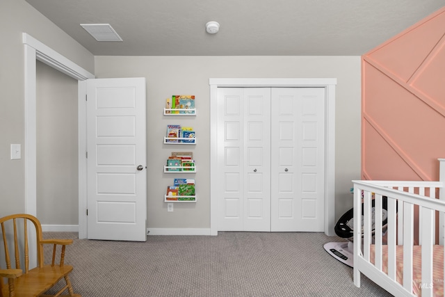 carpeted bedroom with baseboards, a crib, visible vents, and a closet