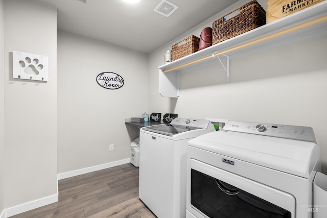 washroom featuring laundry area, visible vents, light wood-type flooring, baseboards, and separate washer and dryer