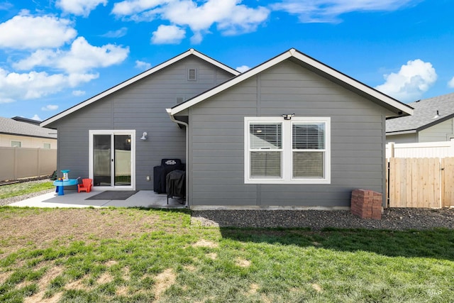 back of property with fence, a lawn, and a patio