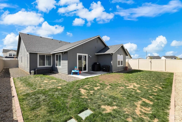 back of property featuring a fenced backyard, a patio, a shingled roof, and a lawn