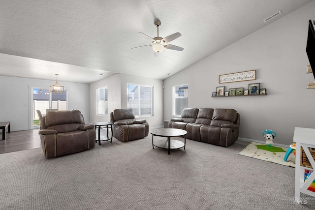 living room with ceiling fan with notable chandelier, carpet flooring, a textured ceiling, and a healthy amount of sunlight