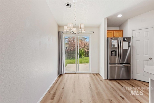 unfurnished dining area with baseboards, visible vents, a notable chandelier, and light wood-type flooring