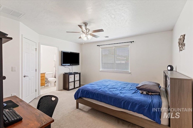 bedroom featuring carpet floors, visible vents, ensuite bathroom, ceiling fan, and a textured ceiling