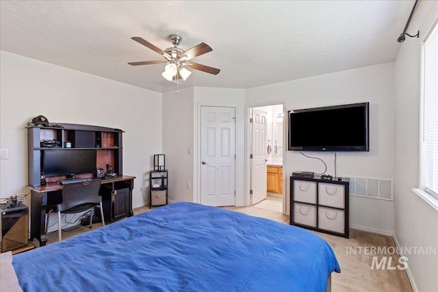 bedroom with visible vents, baseboards, light colored carpet, connected bathroom, and a ceiling fan