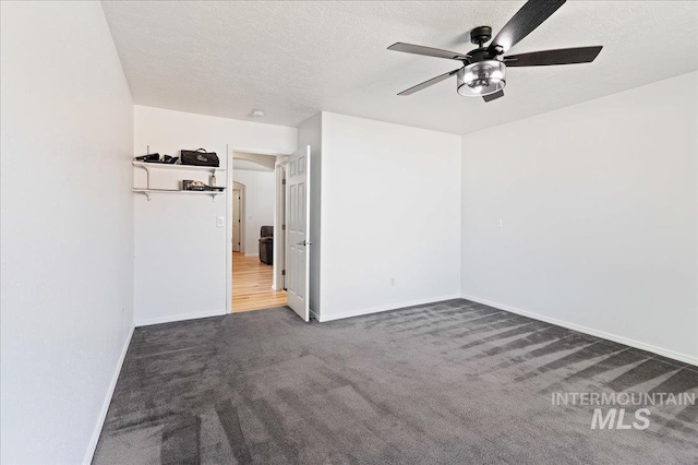 spare room featuring carpet flooring, a ceiling fan, baseboards, and a textured ceiling