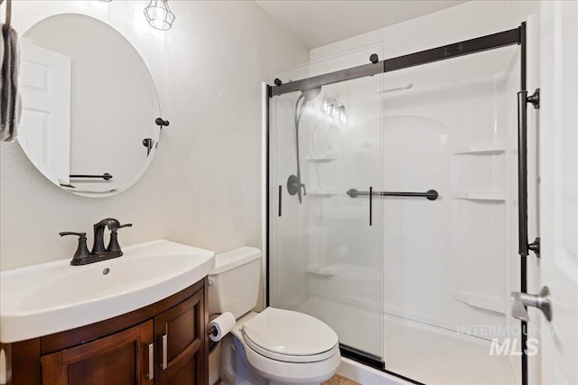 full bath with vanity, a shower stall, and toilet