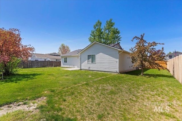 rear view of property featuring a yard and a fenced backyard
