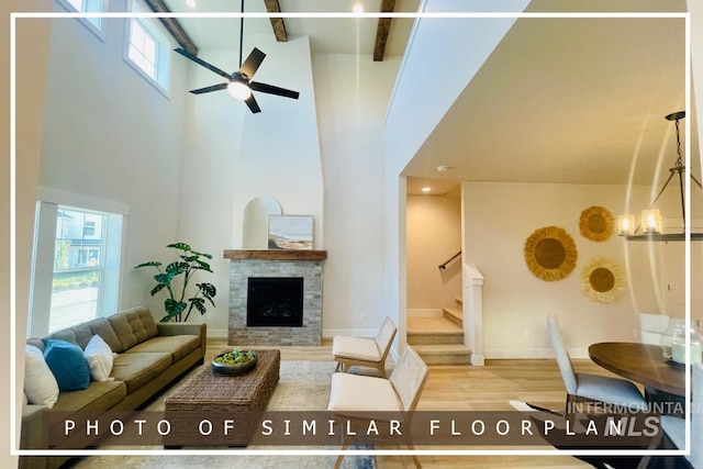 living area featuring baseboards, stairs, beam ceiling, a fireplace, and wood finished floors