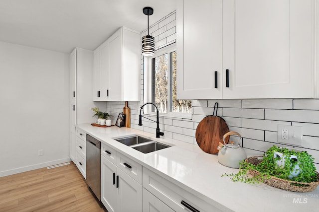 kitchen featuring pendant lighting, sink, stainless steel dishwasher, and white cabinets