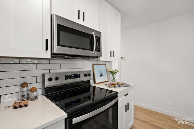 kitchen featuring stainless steel appliances, white cabinetry, tasteful backsplash, and light hardwood / wood-style floors