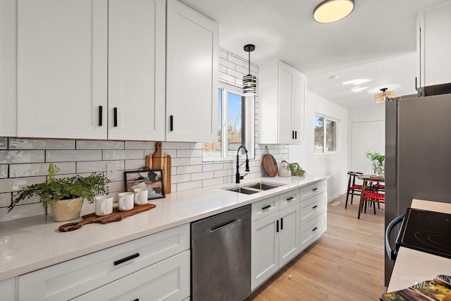 kitchen with pendant lighting, sink, stainless steel appliances, and white cabinets