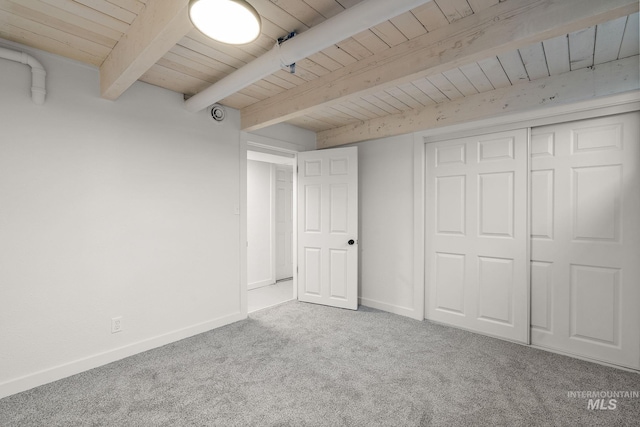 unfurnished bedroom featuring wood ceiling, beam ceiling, and light colored carpet