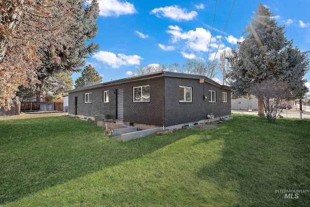 rear view of house with cooling unit and a lawn