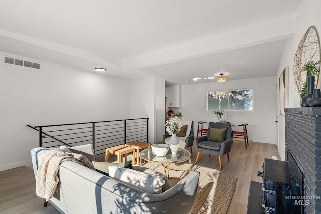 living room with a brick fireplace and hardwood / wood-style floors