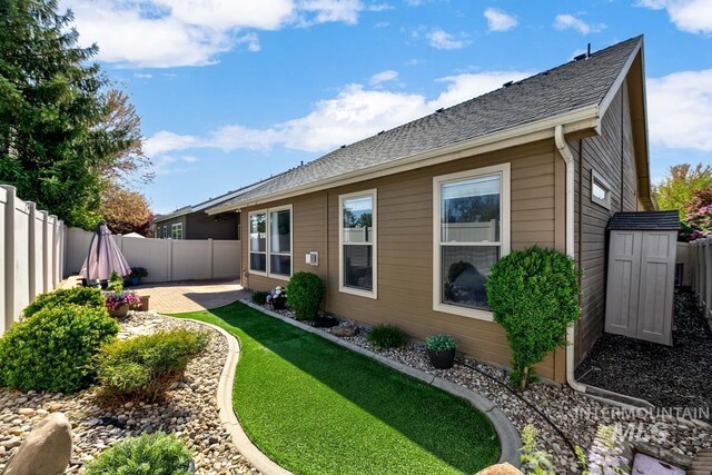 1928 E Mountain Man Dr, Meridian, ID 83646 - rear view of property with roof with shingles, a storage shed, an outdoor structure, a fenced backyard, and a patio