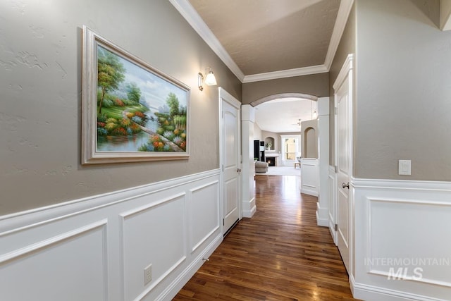 1928 E Mountain Man Dr, Meridian, ID 83646 - hallway with crown molding, arched walkways, wainscoting, a decorative wall, and dark wood-type flooring