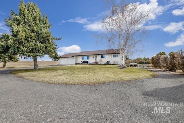 ranch-style house with a garage, a front yard, and aphalt driveway