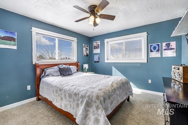 carpeted bedroom featuring multiple windows, a textured ceiling, baseboards, and a ceiling fan