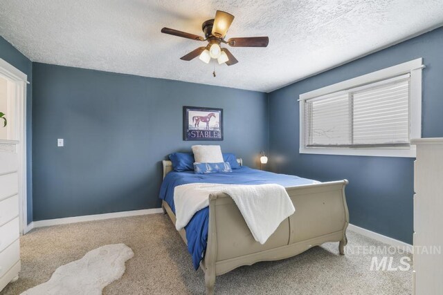 carpeted bedroom with baseboards, a textured ceiling, and a ceiling fan