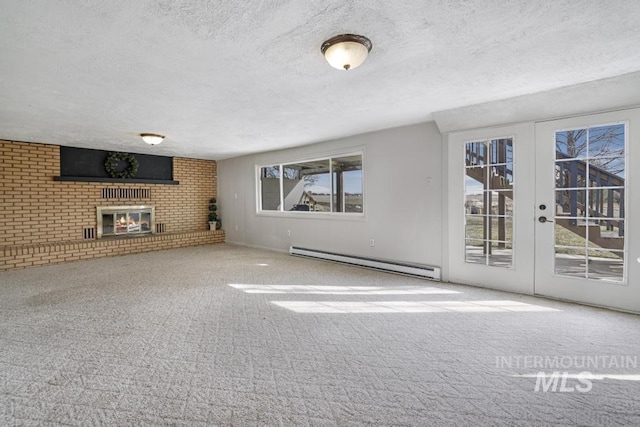 unfurnished living room with a wealth of natural light, carpet flooring, a brick fireplace, and a baseboard radiator