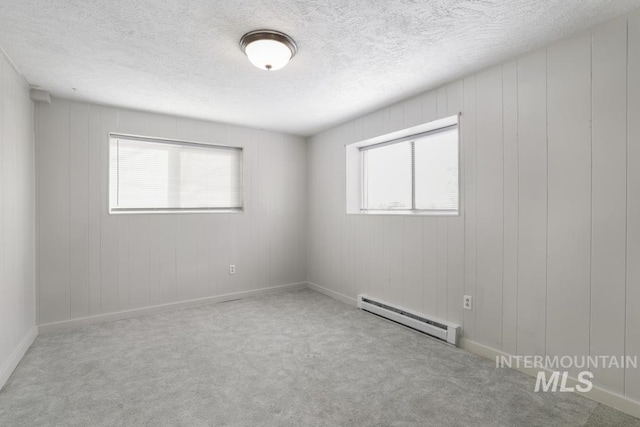 carpeted empty room with a textured ceiling and a baseboard radiator