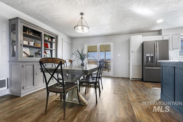 dining room with visible vents, baseboards, a textured ceiling, and dark wood finished floors