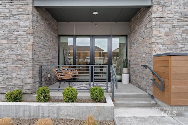 doorway to property featuring covered porch and stone siding