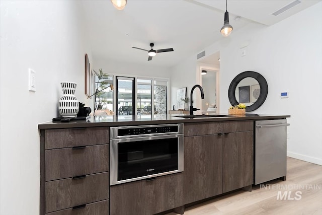 kitchen featuring visible vents, dark countertops, appliances with stainless steel finishes, light wood-type flooring, and a sink