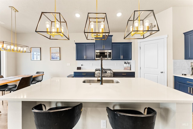 kitchen with a kitchen bar, an island with sink, stainless steel appliances, and blue cabinets