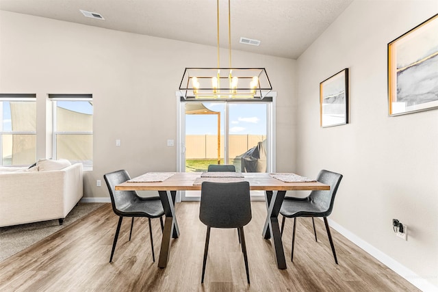 dining room featuring a notable chandelier, light wood-type flooring, and lofted ceiling