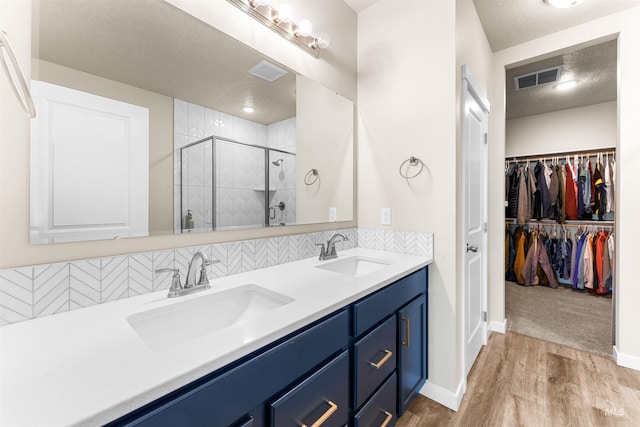 bathroom with a textured ceiling, decorative backsplash, vanity, a shower with shower door, and hardwood / wood-style flooring