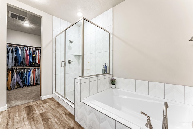 bathroom with shower with separate bathtub, a textured ceiling, and hardwood / wood-style flooring