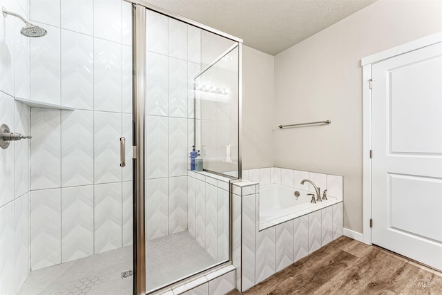 bathroom featuring plus walk in shower, a textured ceiling, and hardwood / wood-style flooring