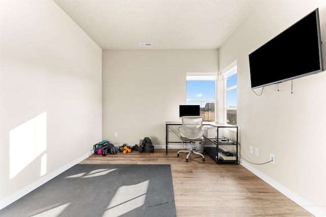 office space with a textured ceiling and light hardwood / wood-style flooring