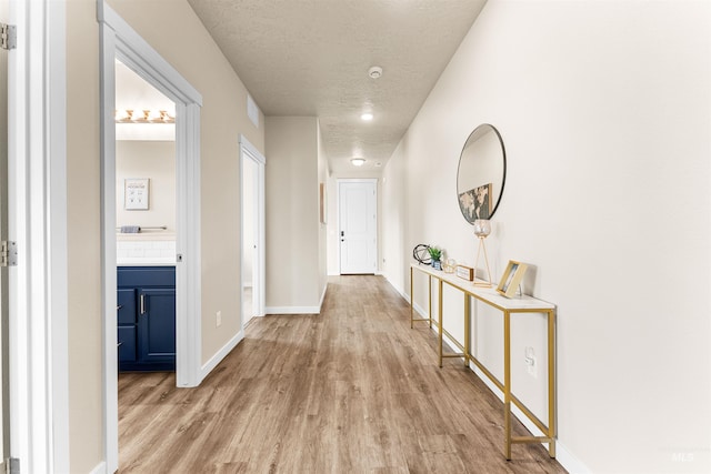 hallway with a textured ceiling and light wood-type flooring