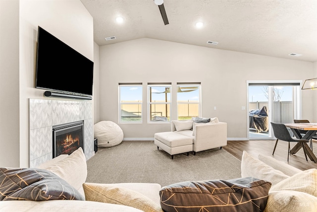 living room featuring a textured ceiling, vaulted ceiling, ceiling fan, wood-type flooring, and a fireplace