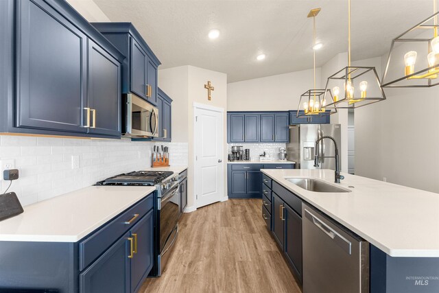 kitchen with blue cabinetry, sink, stainless steel appliances, vaulted ceiling, and decorative light fixtures