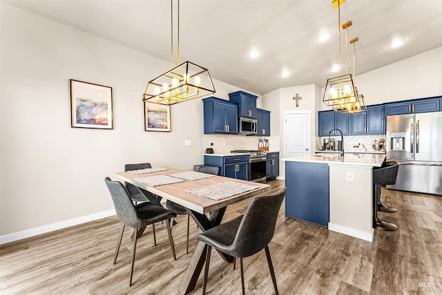 dining room with sink, vaulted ceiling, and hardwood / wood-style flooring