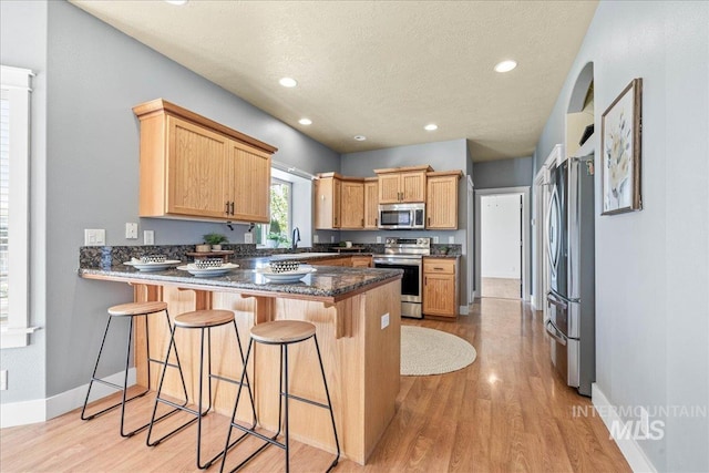 568 S Wooddale Pl, Eagle, ID 83616 - kitchen with stainless steel appliances, a peninsula, a sink, and light wood-style flooring