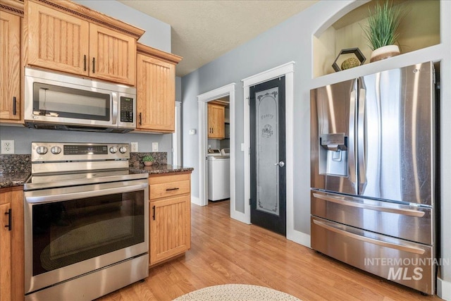 568 S Wooddale Pl, Eagle, ID 83616 - kitchen with stainless steel appliances, light wood-style flooring, dark stone counters, baseboards, and washer / clothes dryer