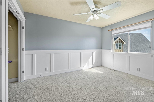 568 S Wooddale Pl, Eagle, ID 83616 - spare room featuring a wainscoted wall, carpet, ceiling fan, and a decorative wall