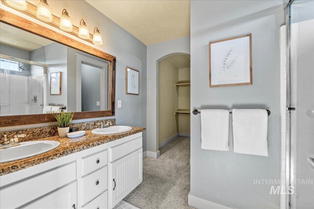 568 S Wooddale Pl, Eagle, ID 83616 - bathroom featuring a tile shower, double vanity, baseboards, and a sink