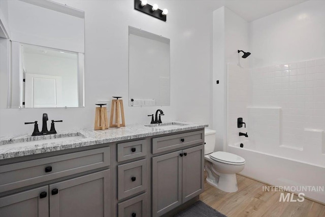 full bath featuring a sink, toilet, wood finished floors, and double vanity