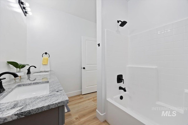 full bathroom with double vanity, wood finished floors, tub / shower combination, and a sink