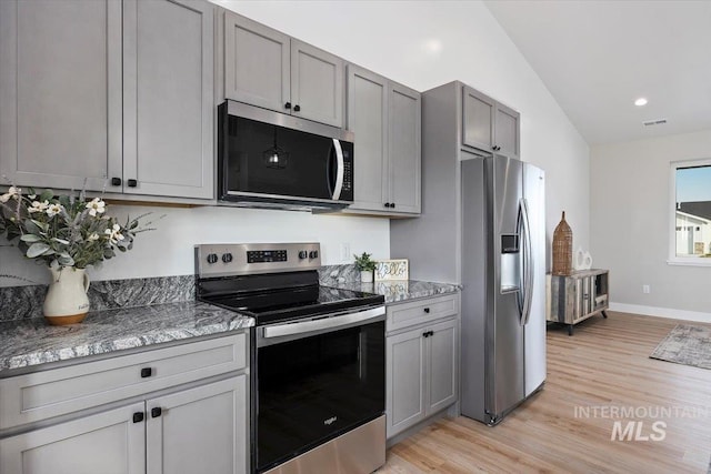 kitchen featuring vaulted ceiling, light wood-type flooring, gray cabinets, and stainless steel appliances