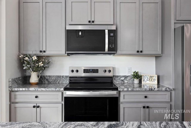 kitchen featuring light stone counters, appliances with stainless steel finishes, and gray cabinets