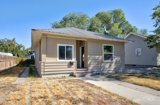 view of front of home featuring metal roof and fence